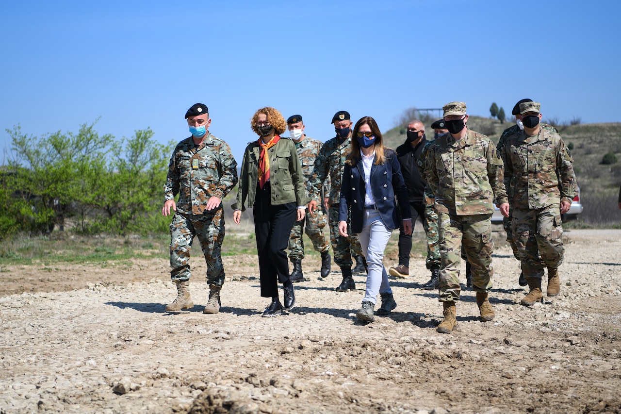 Civilian and military officials tour a military training area.