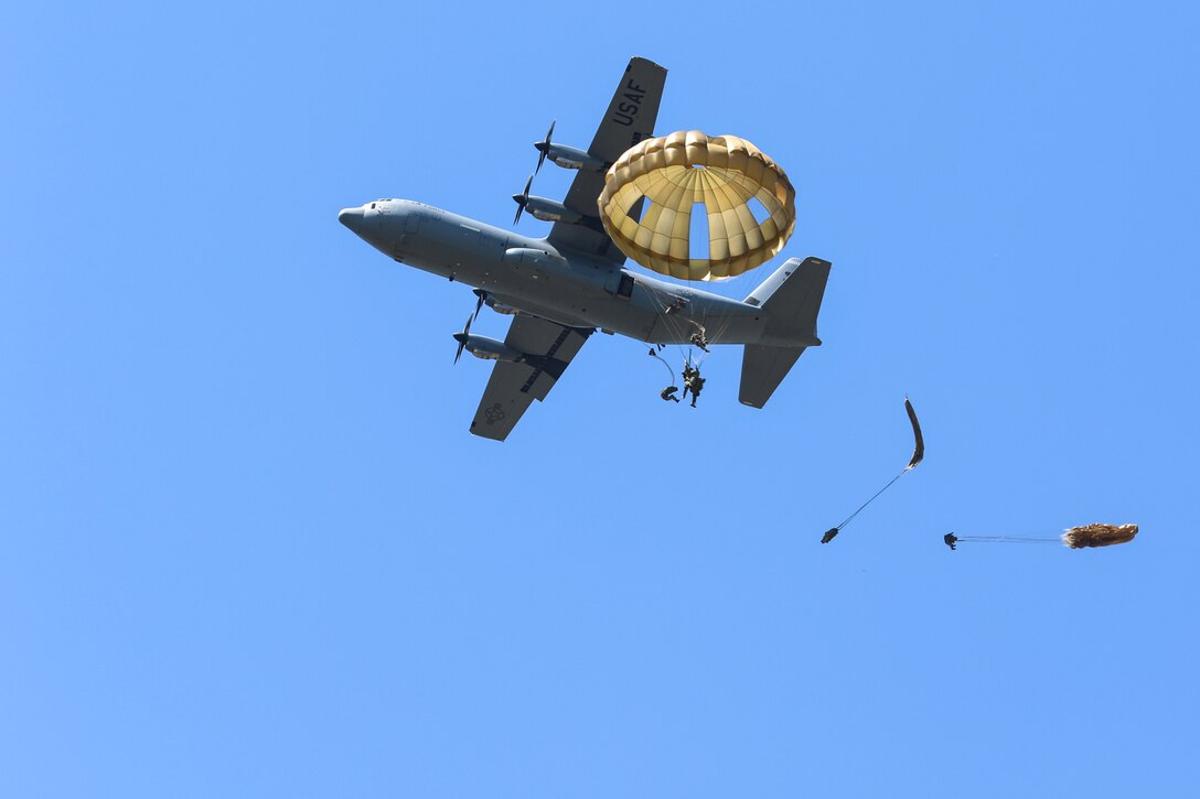 Soldiers parachute from a C-130 airplane.
