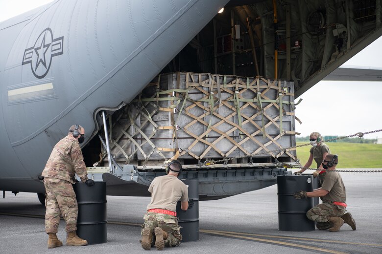 Airmen place barrels underneath aircraft loading bay