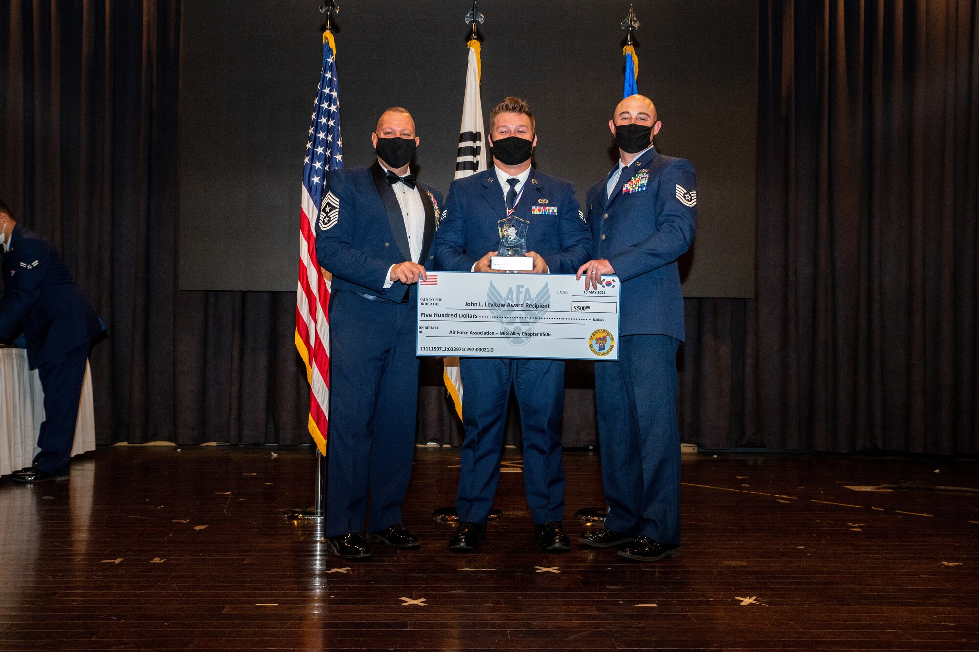 U.S. Air Force Chief Justin Apiticar, 51st Fighter Wing command chief, left, presents the John L. Levitow award to Senior Airman Paden Bailey, 604th Air Support Operations Squadron, middle, during the Airman Leadership School class 21-D graduation at Osan Air Base, Republic of Korea, May 13, 2021.