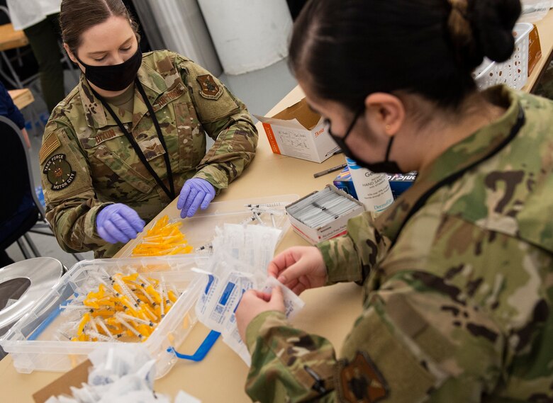 U.S. Air Force Airmen assemble syringes to be used in the distribution of the COVID-19 vaccine inside the pharmacy area of the federally-supported Community Vaccination Center (CVC) at Ford Field in Detroit, Michigan, May 3, 2021. The Ford Field CVC is designed to vaccinate up to 6,000 community members per day. U.S. Northern Command, through U.S. Army North, remains committed to providing continued, flexible Department of Defense support to the Federal Emergency Management Agency as part of the whole-of-government response to COVID-19. (U.S. Air Force photo by Wesley Farnsworth)