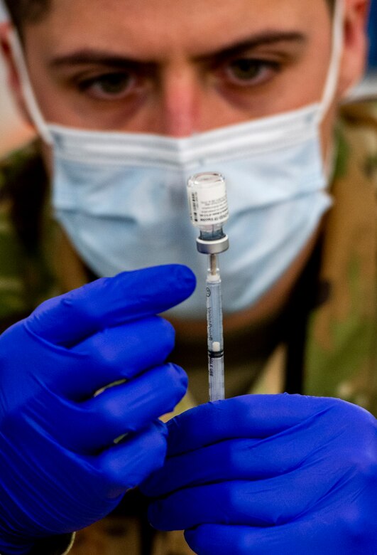 A U.S. Air Force Airman fills a syringe with the COVID-19 Vaccine inside the pharmacy at the federally-supported Community Vaccination Center (CVC) at Ford Field in Detroit, Michigan, May 3, 2021. The Ford Field CVC is designed to vaccinate up to 6,000 community members per day. U.S. Northern Command, through U.S. Army North, remains committed to providing continued, flexible Department of Defense support to the Federal Emergency Management Agency as part of the whole-of-government response to COVID-19. (U.S. Air Force photo by Wesley Farnsworth)