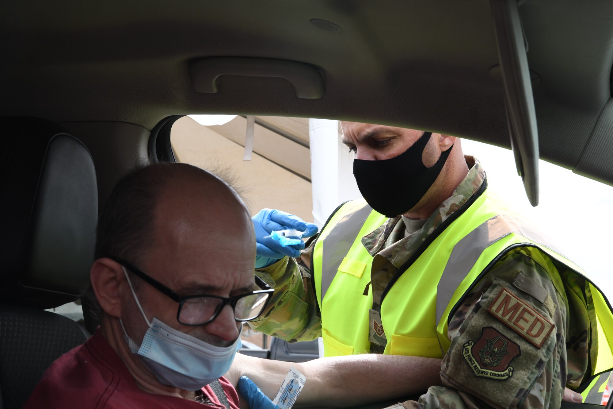 Reserve Airman Tech. Sgt. Ryan Bucher, 944th Fighter Wing medical tech, administers a COVID-19 shot to a Salt River Pima-Maricopa Indian Community resident at the Salt-River Point of Dispensing site, March 26, 2021. Bucher volunteered to use his annual tour time to help the Arizona National Guard administer the vaccine within Arizona communities.