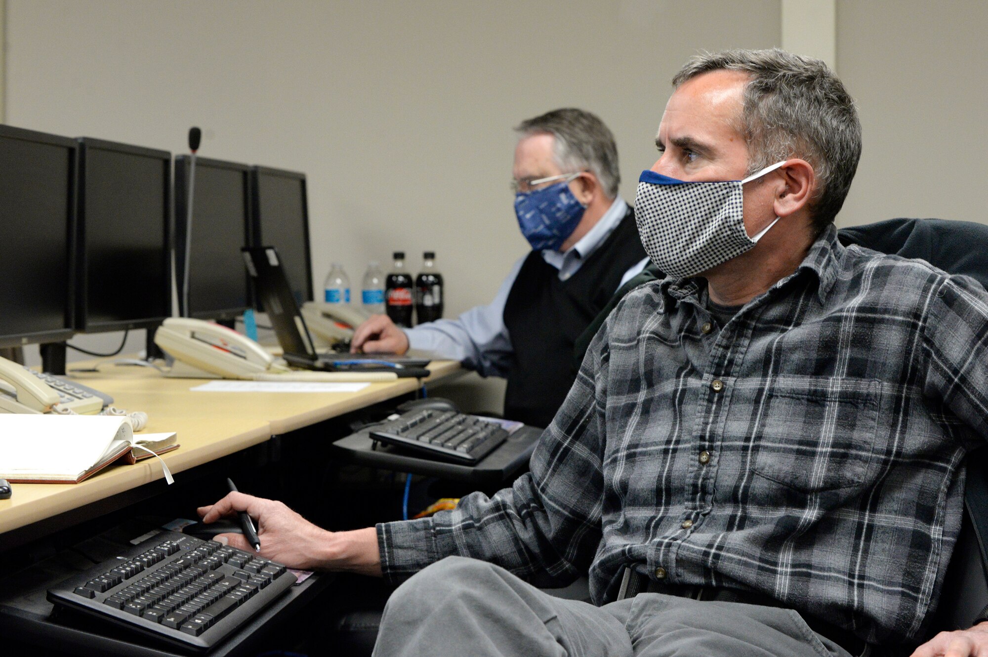 Michael Rives, left, 88th Medical Group medical emergency manager and William Neitzke, 88th Air Base Wing Incident Command Center director of safety and planning listen to a daily conference call with Col. Thomas P. Sherman, 88 ABW commander, while monitoring the COVID-19 pandemic at Wright-Patterson Air Force Base, Ohio, May 5, 2020. (U.S. Air Force photo by Ty Greenlees)