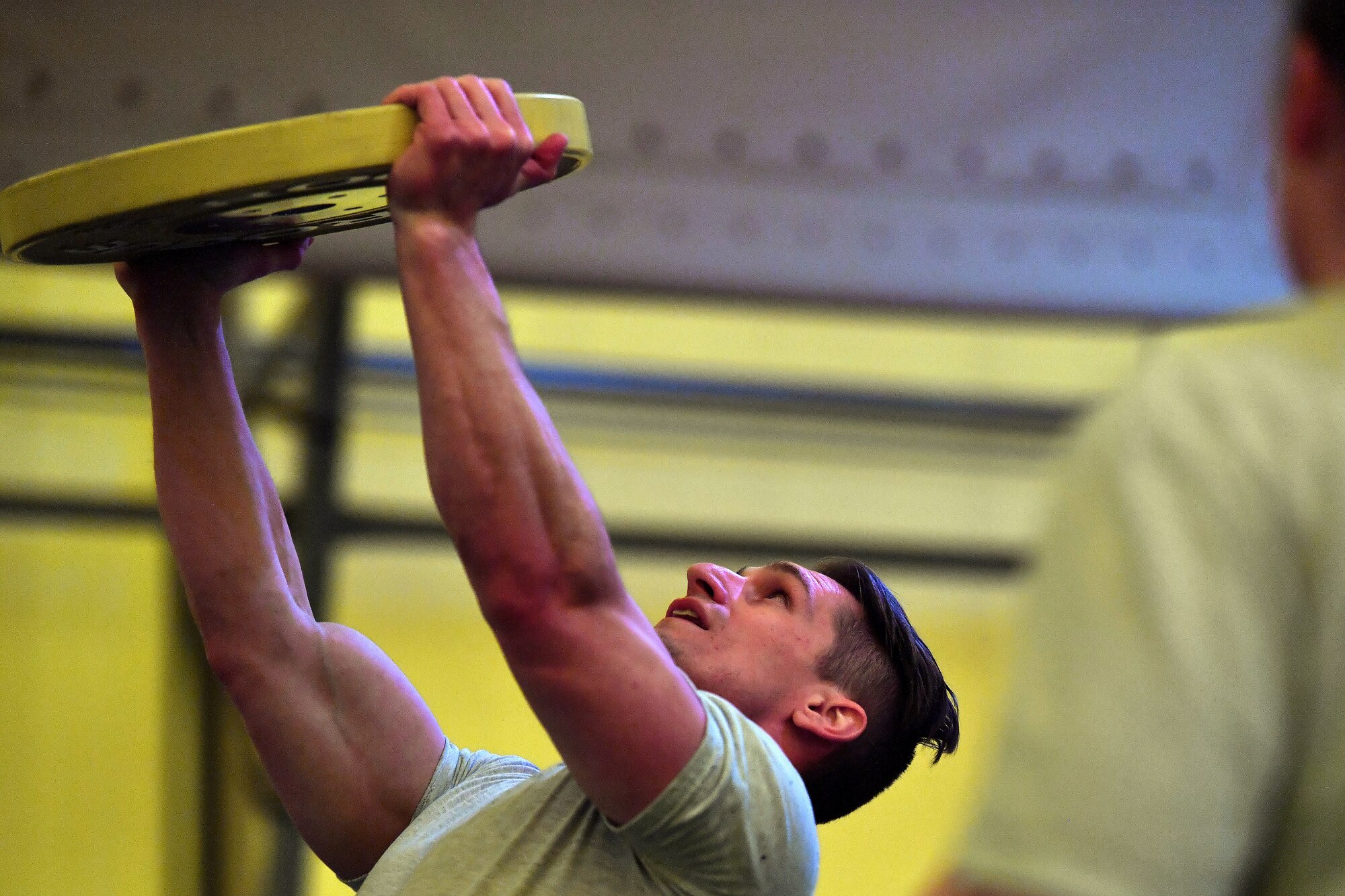 Member completes an overhead press with a 35 pound weight