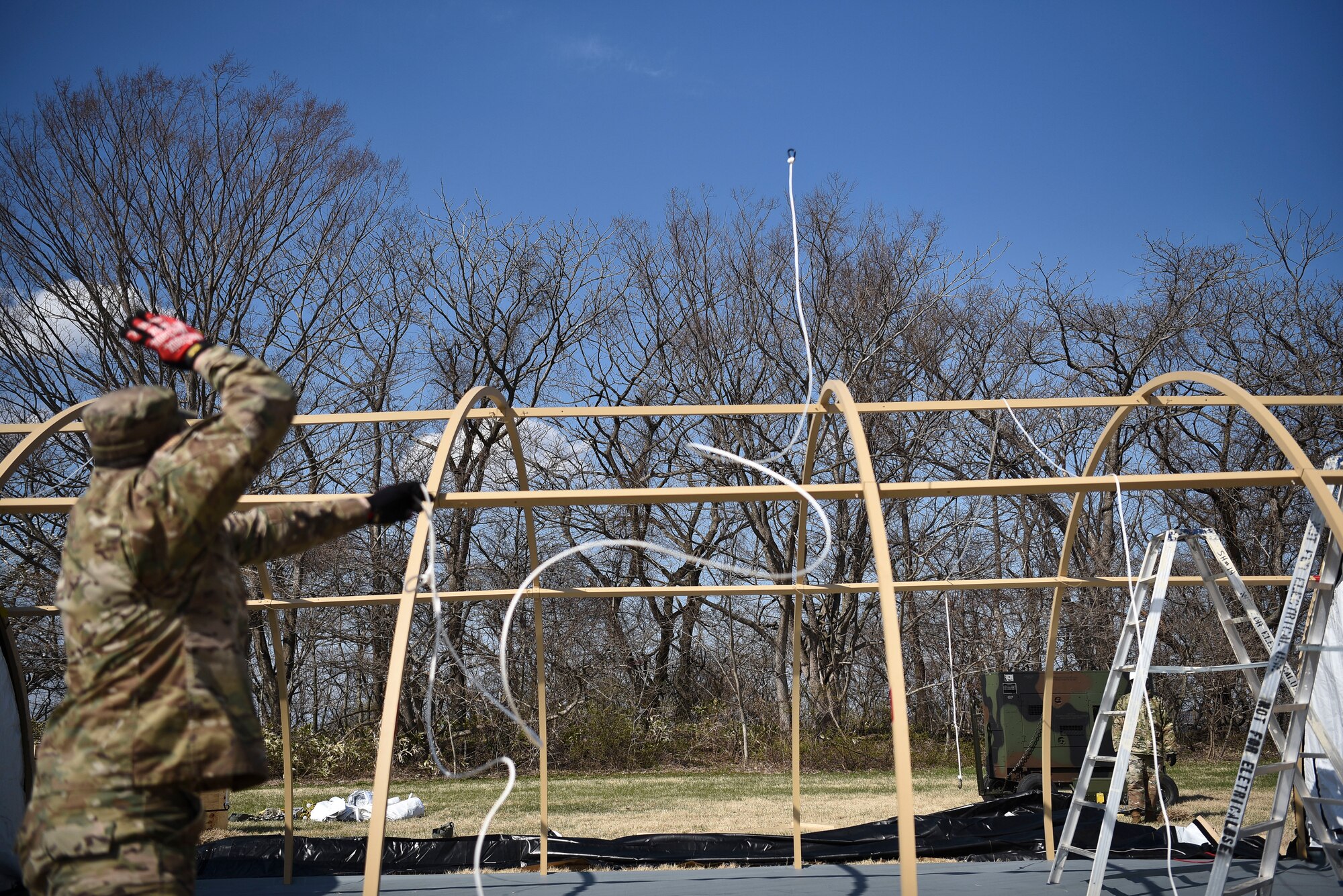 U.S. Air Force Staff Sgt. Thomas Wilks, a 35th Civil Engineer Squadron electrical power production craftsman, tosses a carabiner over a Small Shelter System structure during Agile Combat Employment (ACE) training at Misawa Air Base, Japan, April 8, 2021.