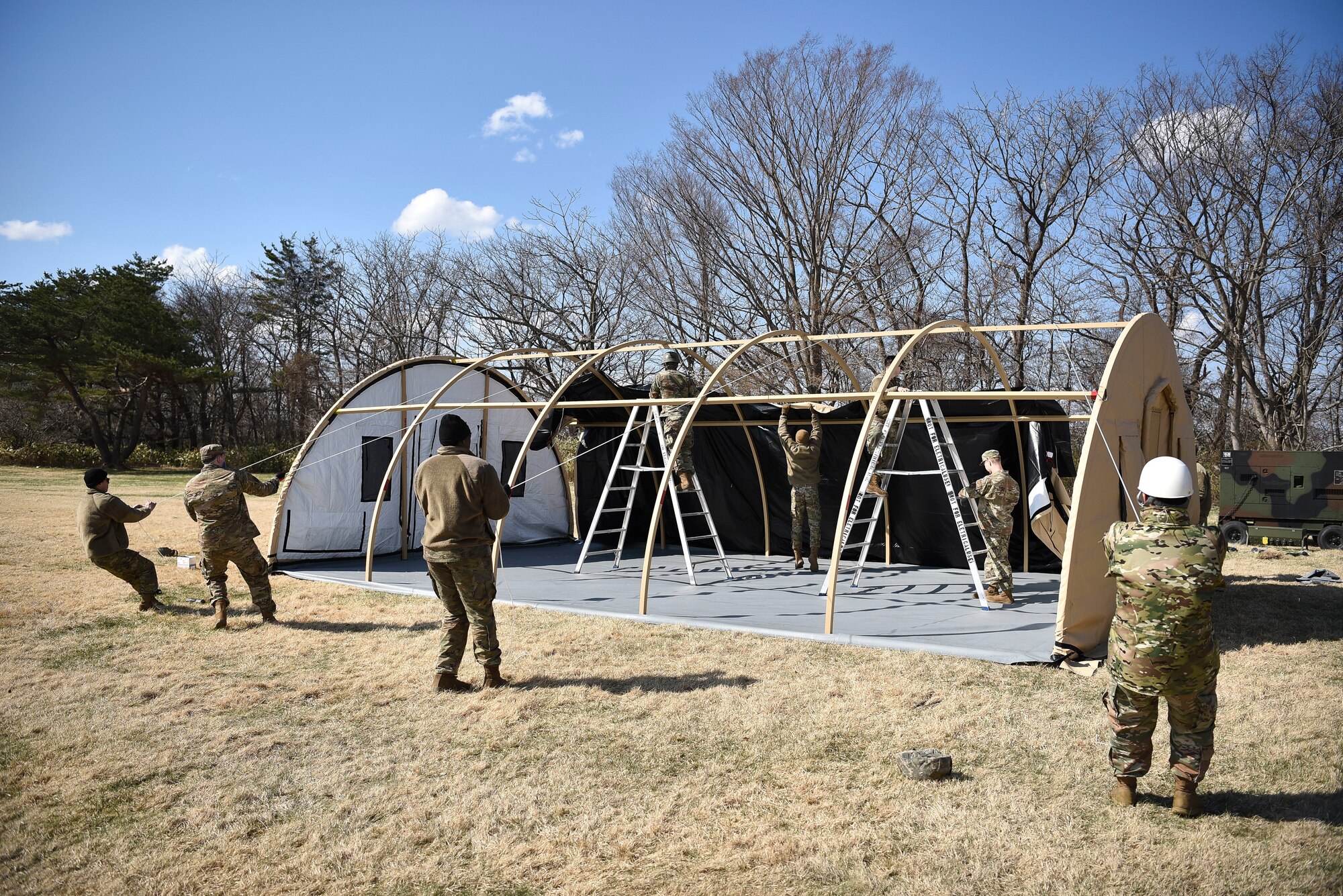 U.S. Air Force Airmen assigned to the 35th Fighter Wing, participating in Agile Combat Employment (ACE) training, pull a tent’s tarp over a structure at Misawa Air Base, Japan, April 8, 2021.