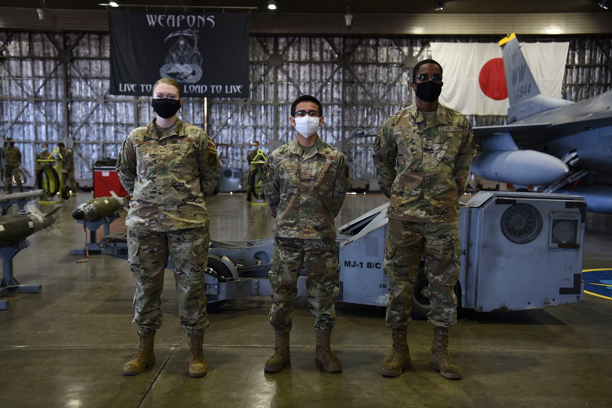 U.S. Air Force Staff Sgt. Kayla Faragher, Senior Airman Victor Odom and Senior Airman Bruno Dusabe, 14th Aircraft Maintenance Unit personnel, stand ready to load munitions onto an F-16 Fighting Falcon during the first quarter load competition at Misawa Air Base, Japan, April 23, 2021.