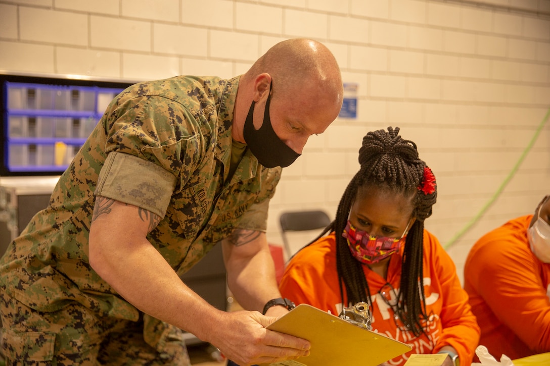 U.S. Navy Lt. J.G. Joseph Kolaszewski, from 2d Marine Division based out of Camp Lejeune, North Carolina, explains procedures to a nurse with University of Tennessee Health Science Center at the Memphis Community Vaccination Center in Memphis, Tennessee, May 12, 2021.