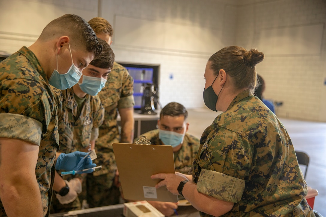 U.S. Navy Lt. Rebecca Gerena, from 2d Marine Division base out of Camp Lejeune, North Carolina, explains procedures to Navy Corpsman at the Memphis Community Vaccination Center in Memphis, Tennessee, May 12, 2021.