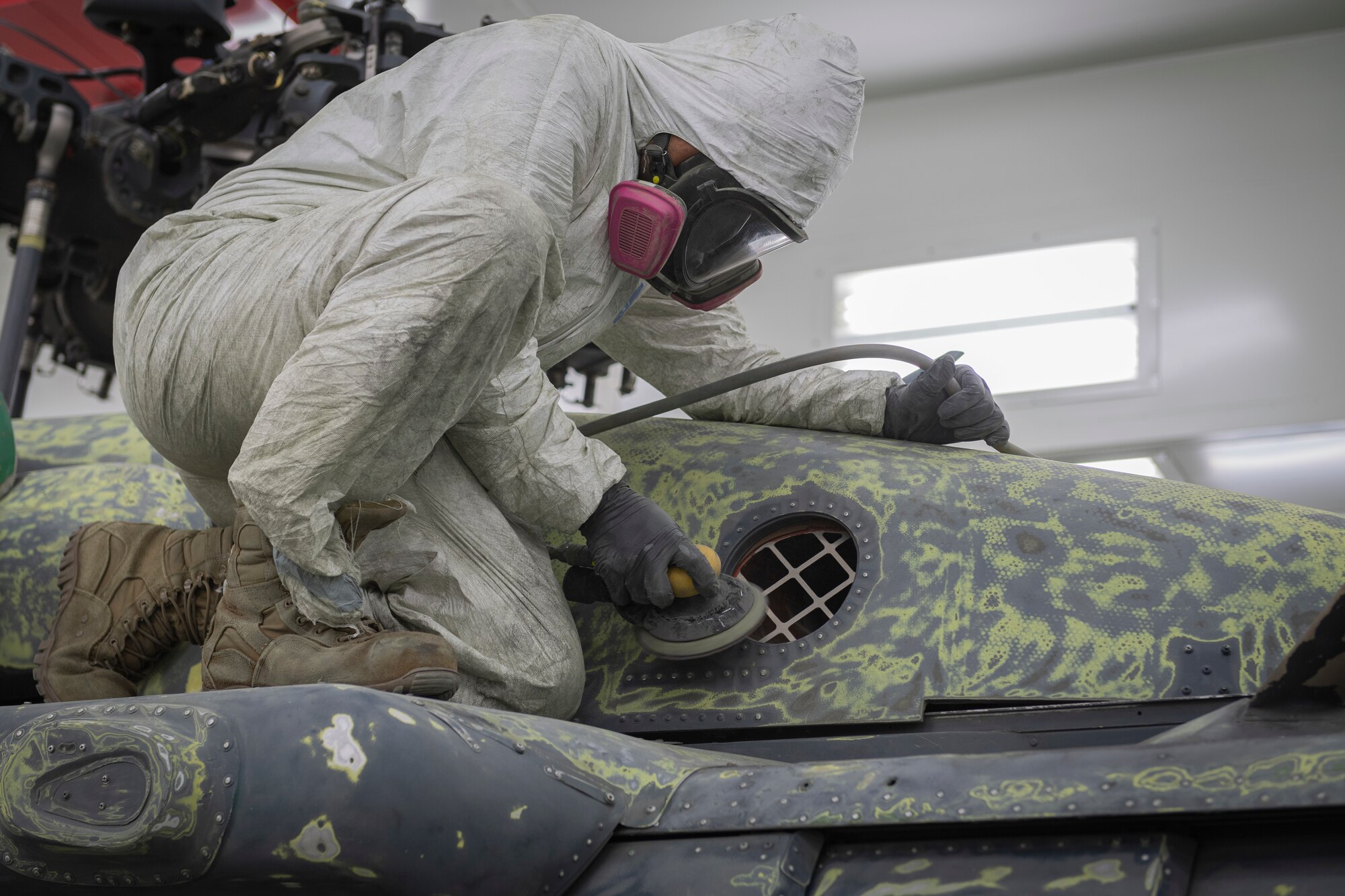 Photo of an Airman sanding a helicopter