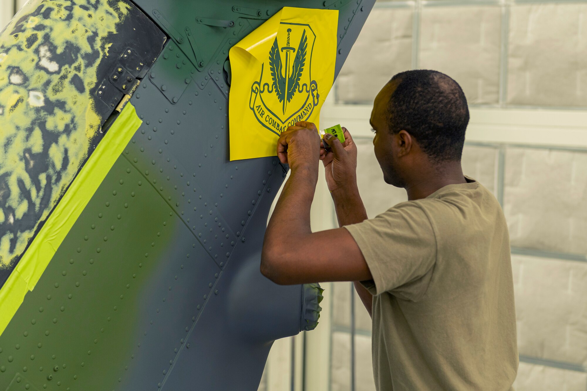 Photo of an Airman placing a stencil on a helicopter