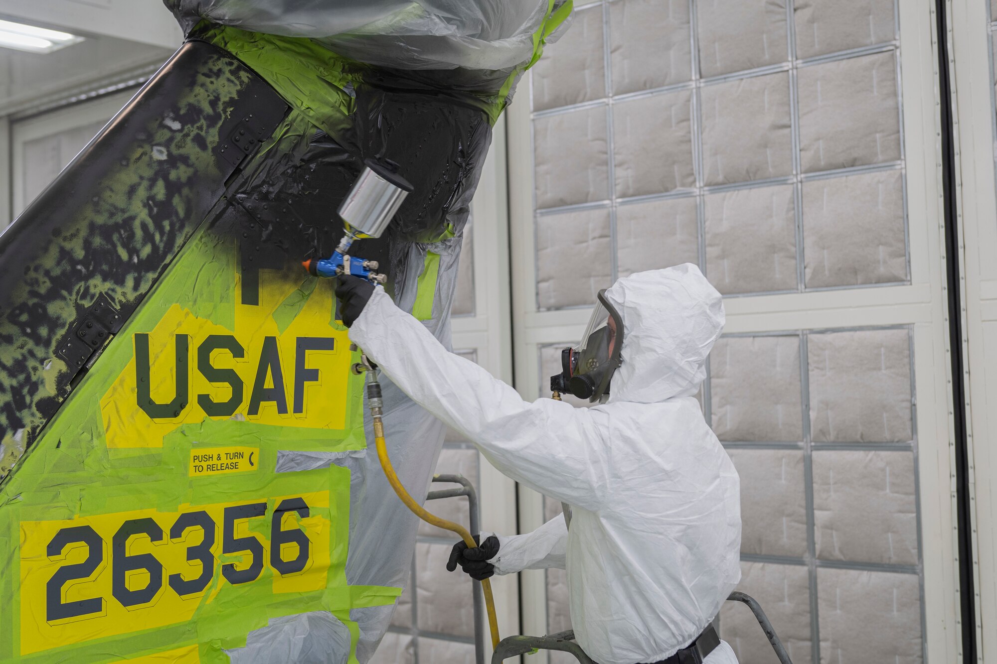 Photo of an Airman painting a helicopter