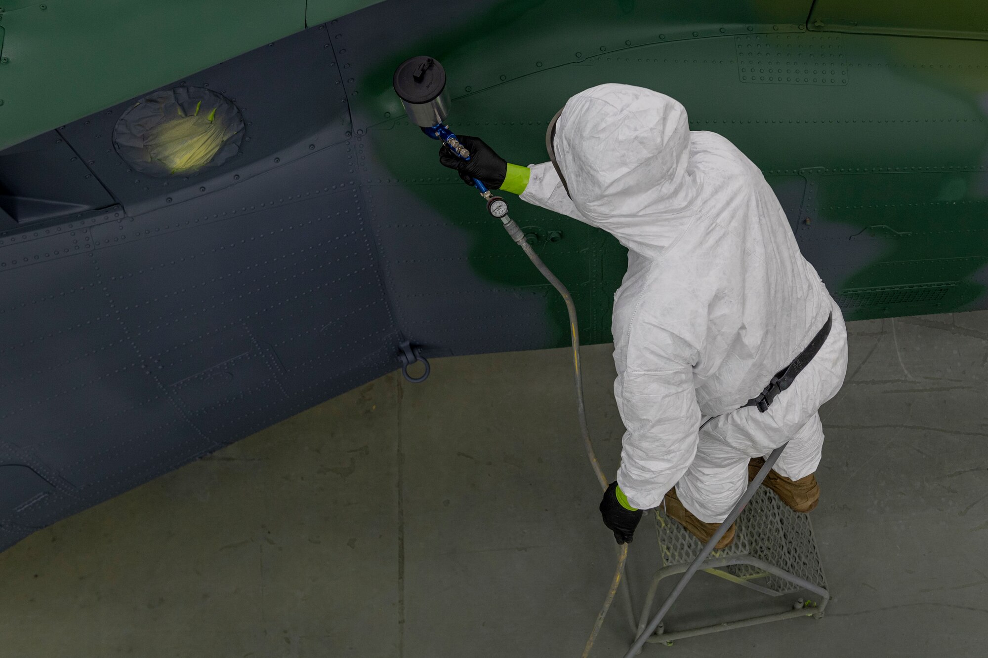 Photo of an Airman painting a helicopter