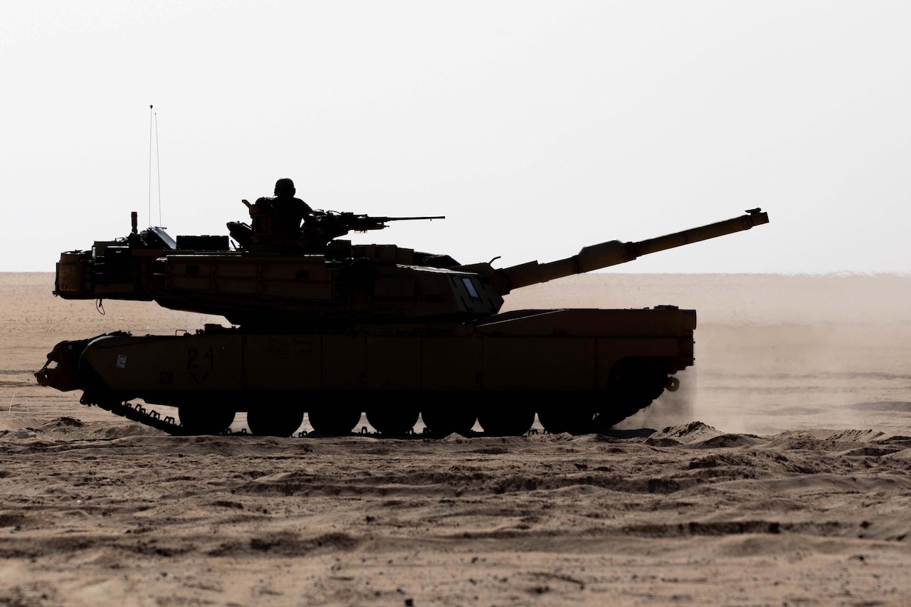 A tank rolls through the desert.