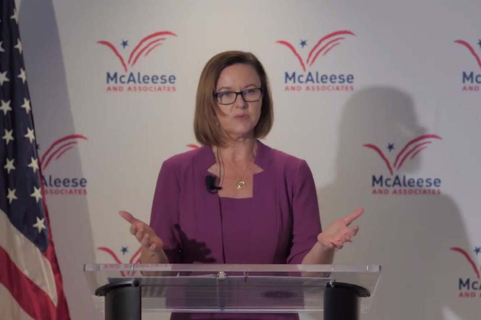 A woman standing at a lectern speaks.
