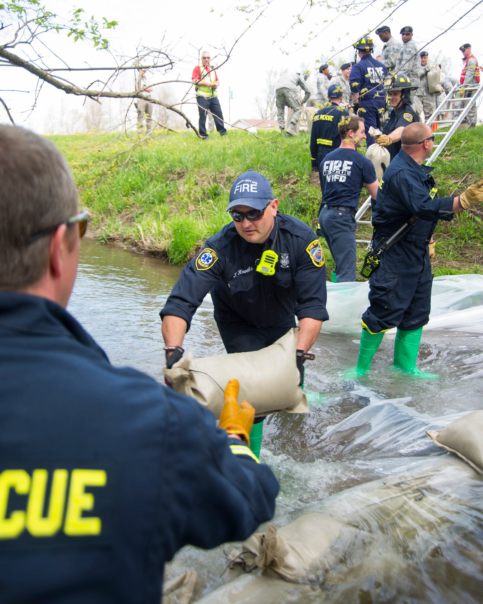 Tim Howells, 788th Civil Engineering Fire Department, passes a sandbag on as part of an assembly line helping to build a dam in Hebble Creek May 2, 2018, on Wright-Patterson Air Force Base, Ohio. The project was part of a base exercise used to train personnel in emergency response. In this case, a simulated fuel spill. (U.S. Air Force photo by R.J. Oriez)