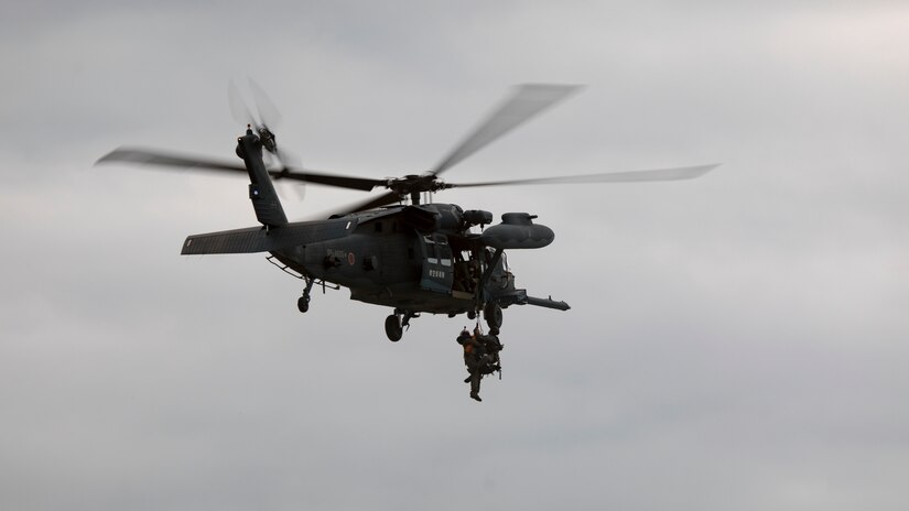 A helicopter hoists a Marine by a rope.