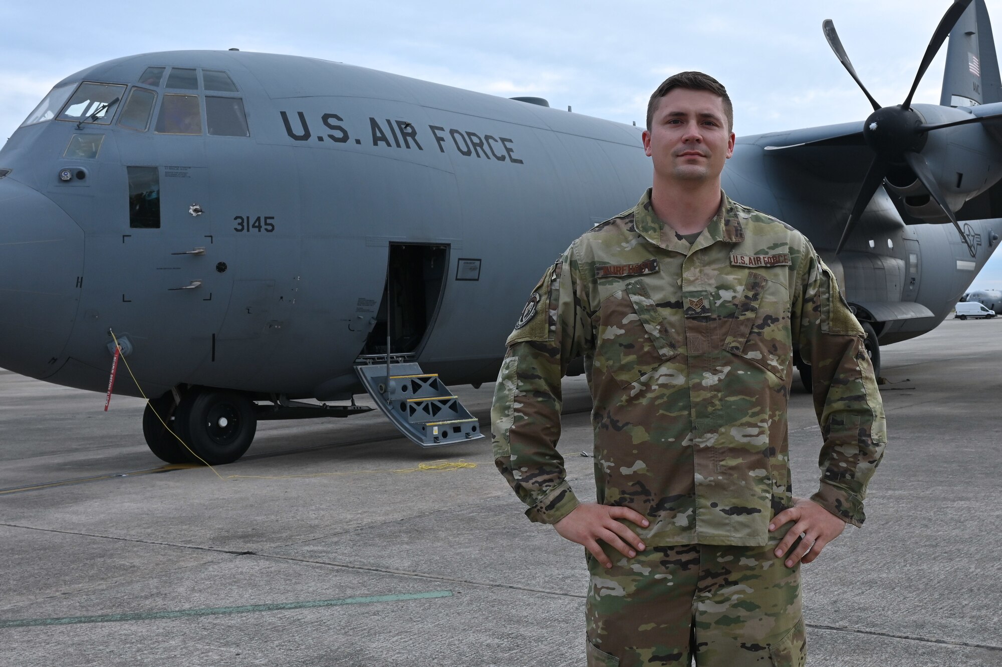 a man poses in front of a plane