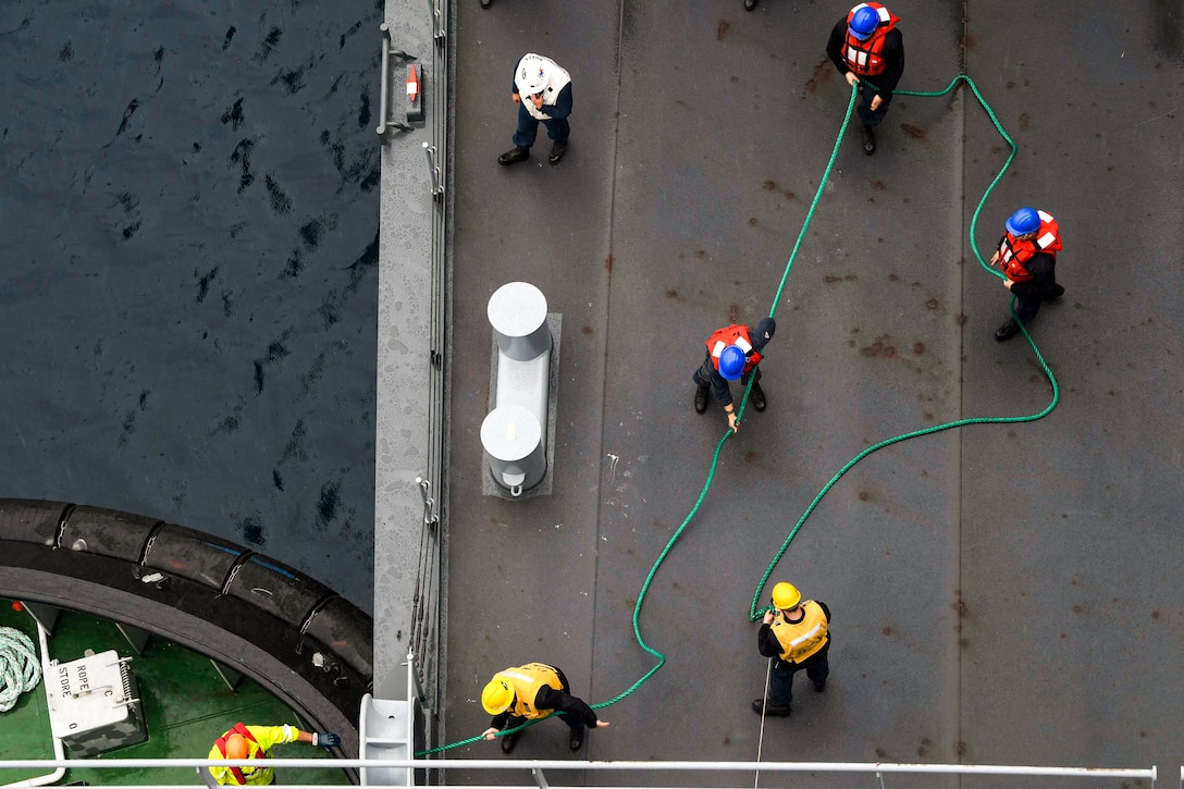 Sailors pull a line on a ship.