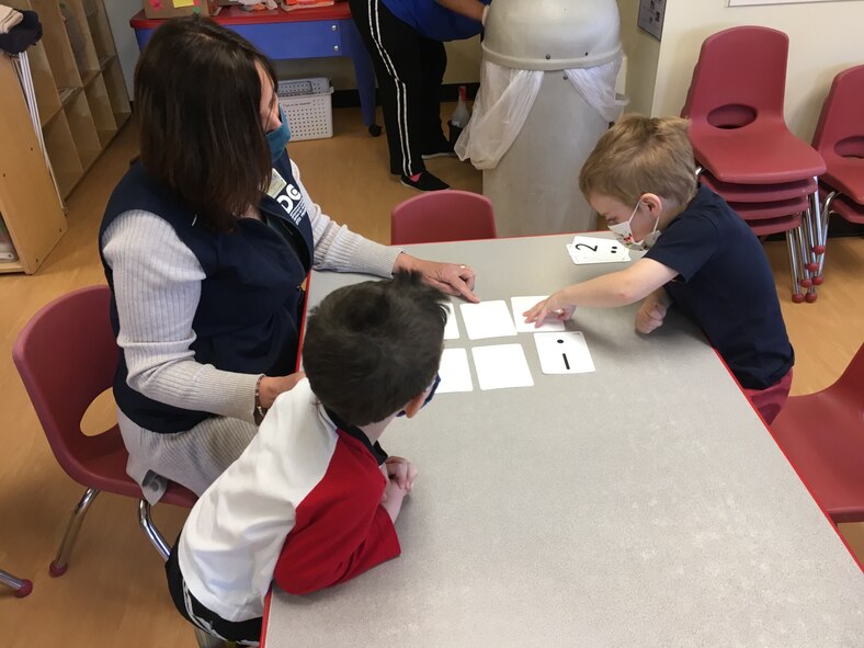 Gail Schultz, 66th Force Support Squadron Child and Youth Program assistant, plays a card game with Jameson Hagerty, right, and William Vergato, at the Child Development Center at Hanscom Air Force Base, Mass., May 14. Specialists from the 66 FSS are continuing to work closely with Public Health officials to increase enrollment capacities at child care centers across the installation. (Courtesy Photo)