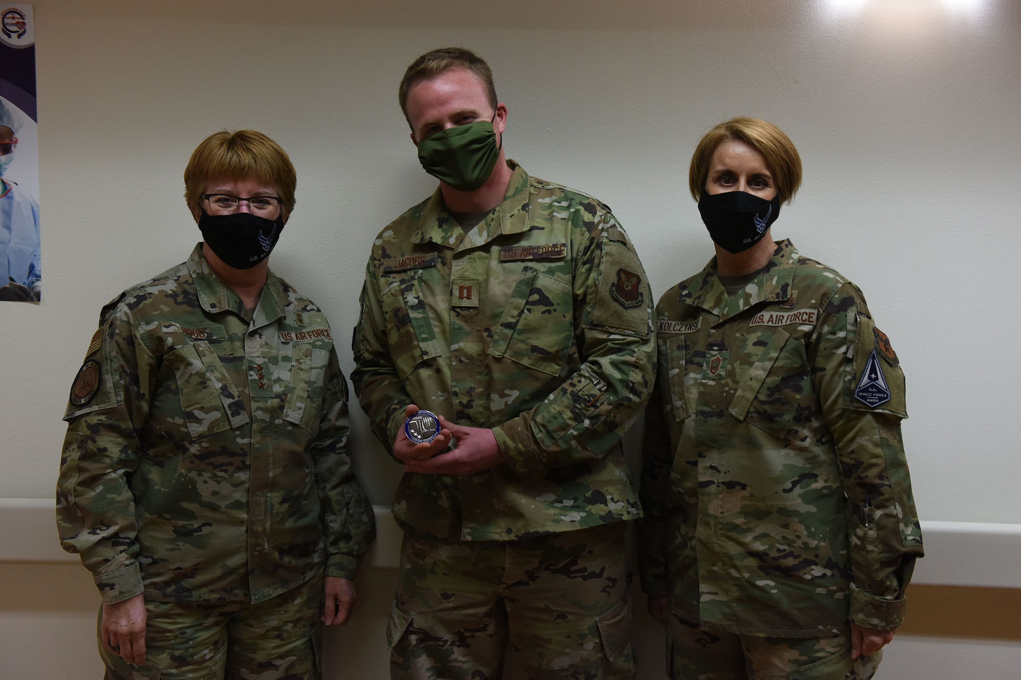 Lt. General Dorothy Hogg, U.S. Air Force surgeon general and Chief Master Sgt. Dawn Kolczynski, medical enlisted force and enlisted corps chief, pose for a photo with Capt. Brennan Jacobs, 341st Medical Group pharmacist, after receiving a coin for excellence April 29, 2021 at the base clinic at Malmstrom Air Force Base, Mont.