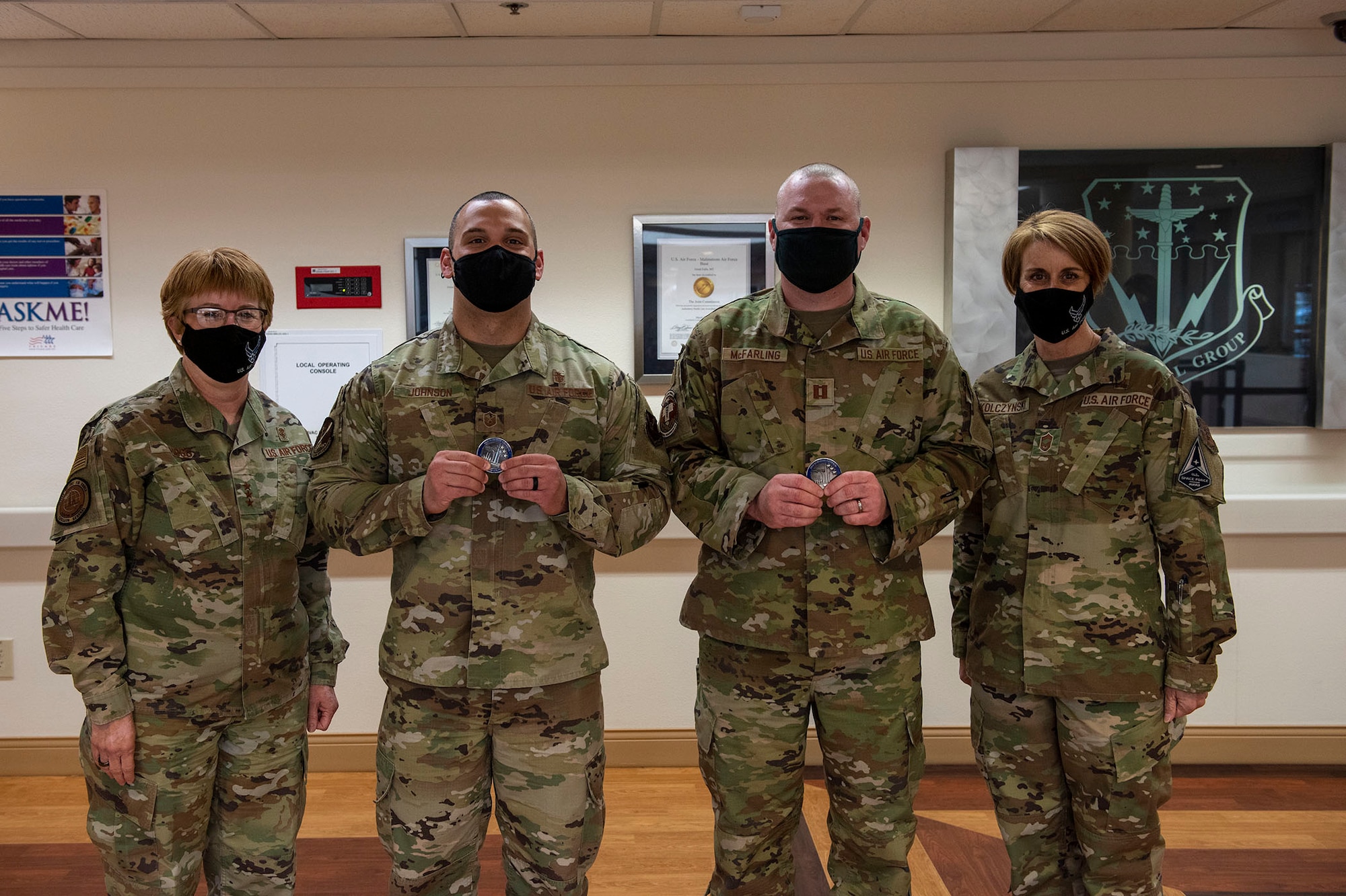 Lt. Gen. Dorothy Hogg, U.S. Air Force surgeon general and Chief Master Sgt. Dawn Kolczynski, medical enlisted force and enlisted corps chief, pose for a photo with Master Sgt. Dustin Johnson, 341st Medical Group superintendent and Capt. Phillip McFarling, 341st Medical Group registered nurse, after they received coins for exceptional performance April 29, 2021 at the basic clinic at Malmstrom Air Force Base, Mont.