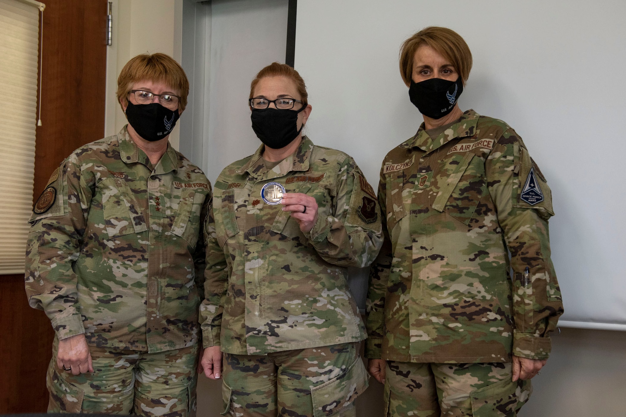 Lt. General Dorothy Hogg, U.S. Air Force surgeon general and Chief Master Sgt. Dawn Kolczynski, medical enlisted force and enlisted corps chief, pose for a photo with Maj. Joy Tesei, 341st Medical Group Physician Assistant after she is coined for exceptional performance April 29, 2021 at the base clinic at Malmstrom Air Force Base, Mont.