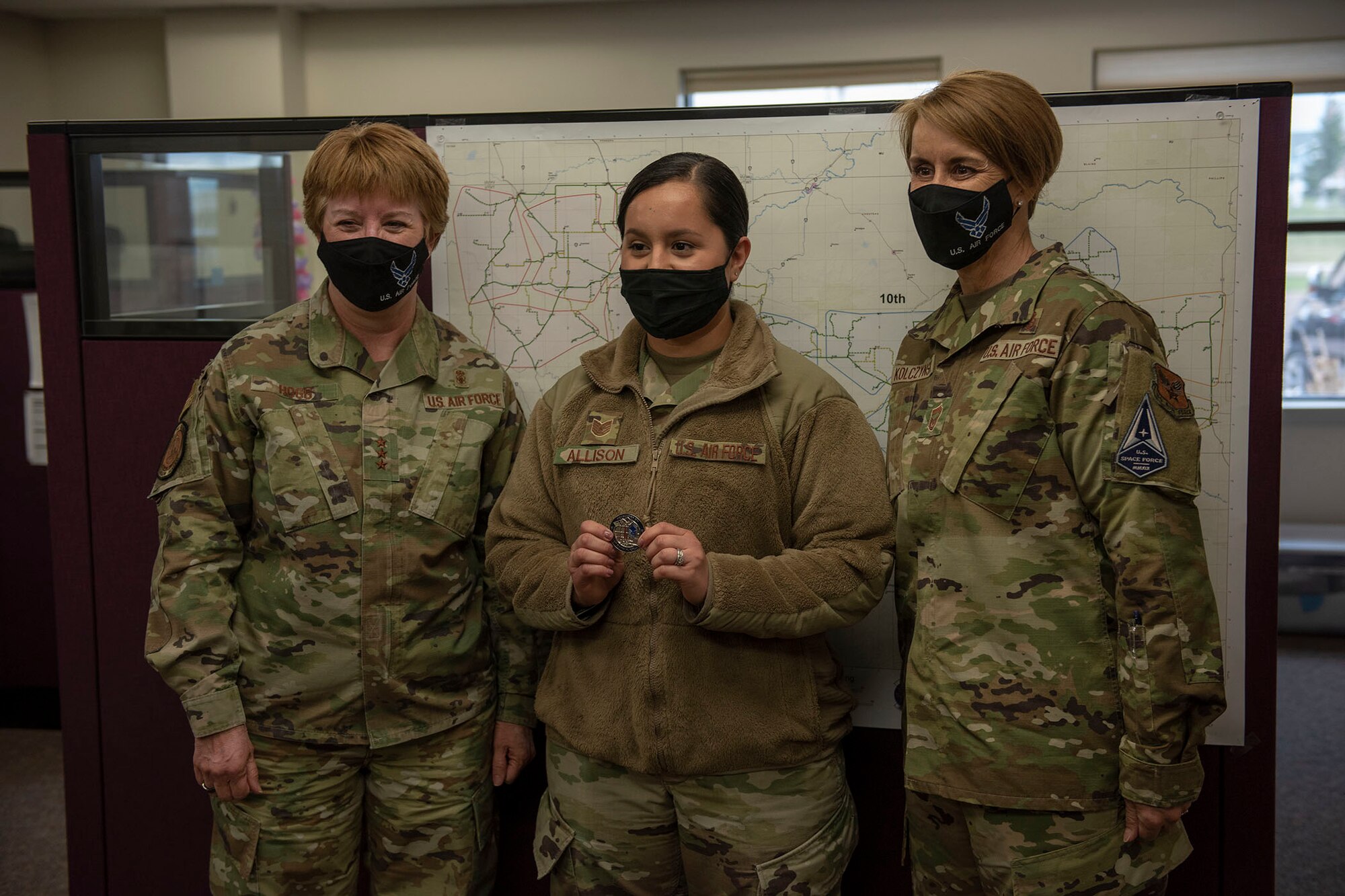 Lt. General Dorothy Hogg, U.S. Air Force surgeon general and Chief Master Sgt. Dawn Kolczynski, medical enlisted force and enlisted corps chief, pose for a photo with Tech Sgt. Alejandra Allison, 341st Medical Group public health supervisor, after Allison received a coin for exceptional performance April 29, 2021 at Malmstrom Air Force Base, Mont.