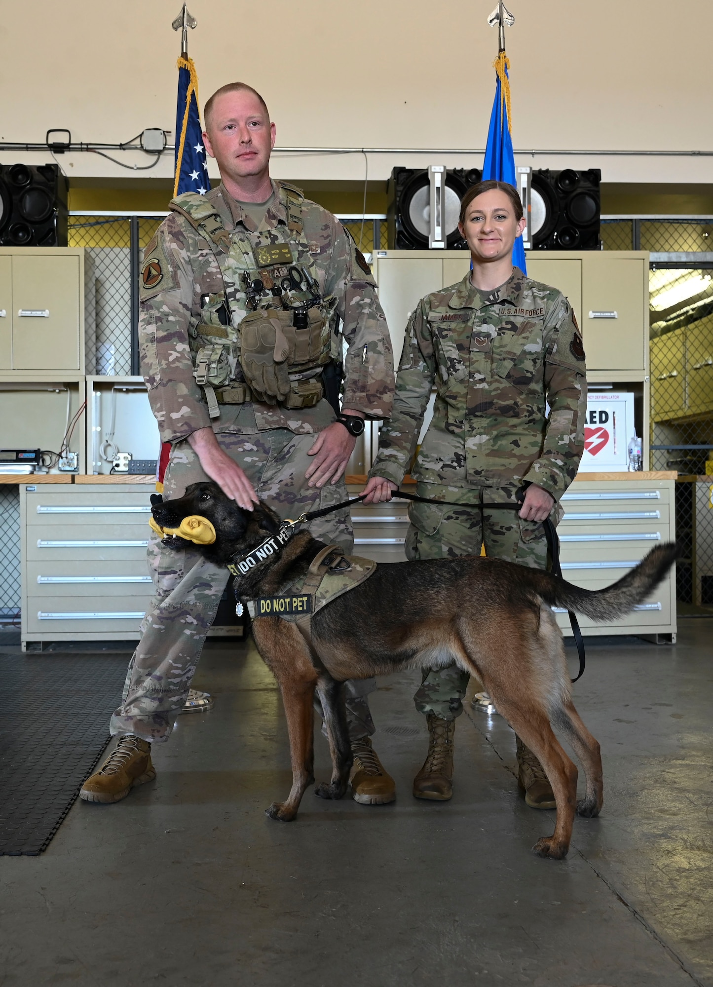 U.S. Air Force Master Sgt. Dustin Weeks, 14th Security Forces Squadron and Staff Sgt. Amber James, 14th Security Forces Squadron Military Working Dog handler, stand with Military Working Dog Ooleg #W136 during the K-9’s retirement ceremony, May 14, 2021, on Columbus Air Force Base, Miss. Weeks presented Ooleg his final bone as a symbol of his final reward, while on active duty. (U.S. Air Force photo by Airman 1st Class Jessica Haynie)