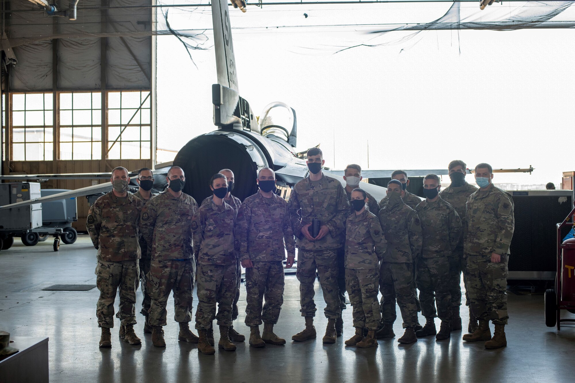 A photo of Col T Sullivan posing with Maintenance Group in front of a jet.