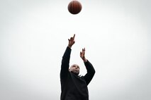 Civilian man throws basketball into air.