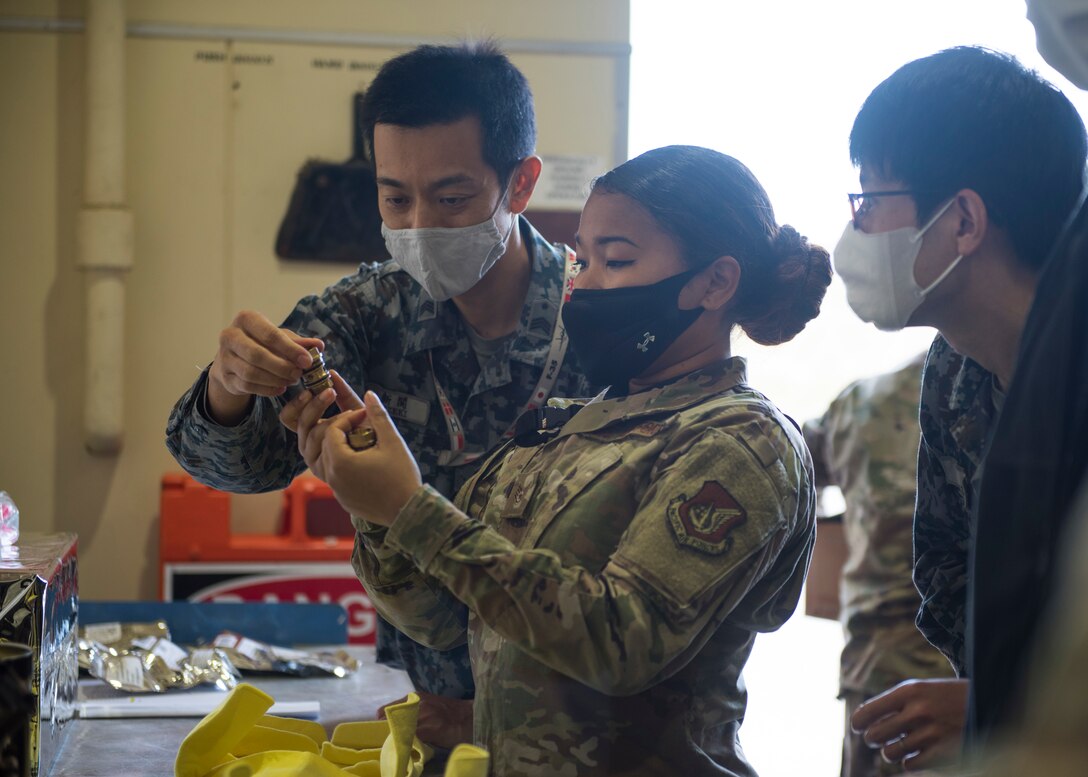 Men and Women in uniform look at small F-35 parts