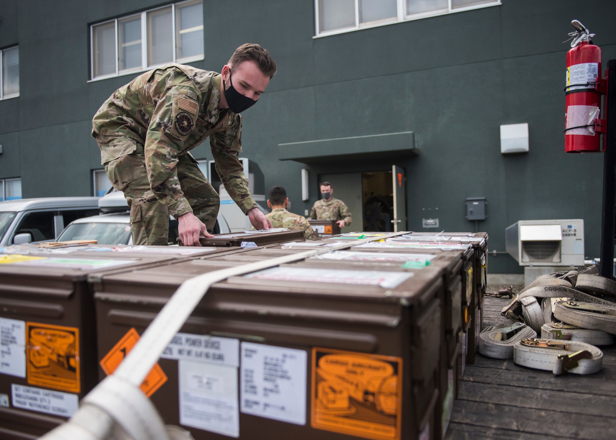 Man in uniform places boxes of F-35 egress parts down onto a truck bed.