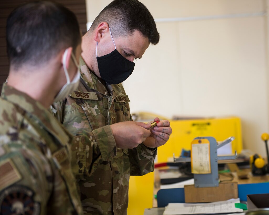 Men in uniform look at small F-35 egress parts.