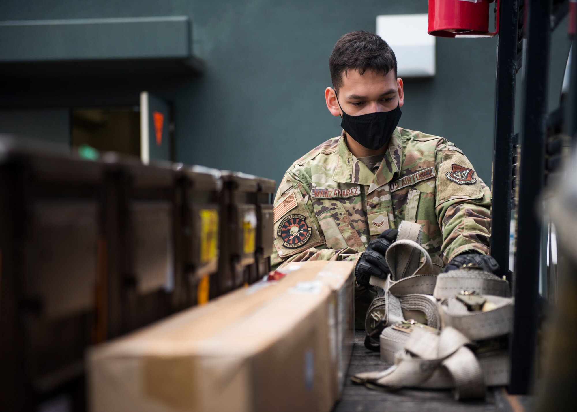 Man in military uniform grabs ropes to secure shipment of F-35 parts.