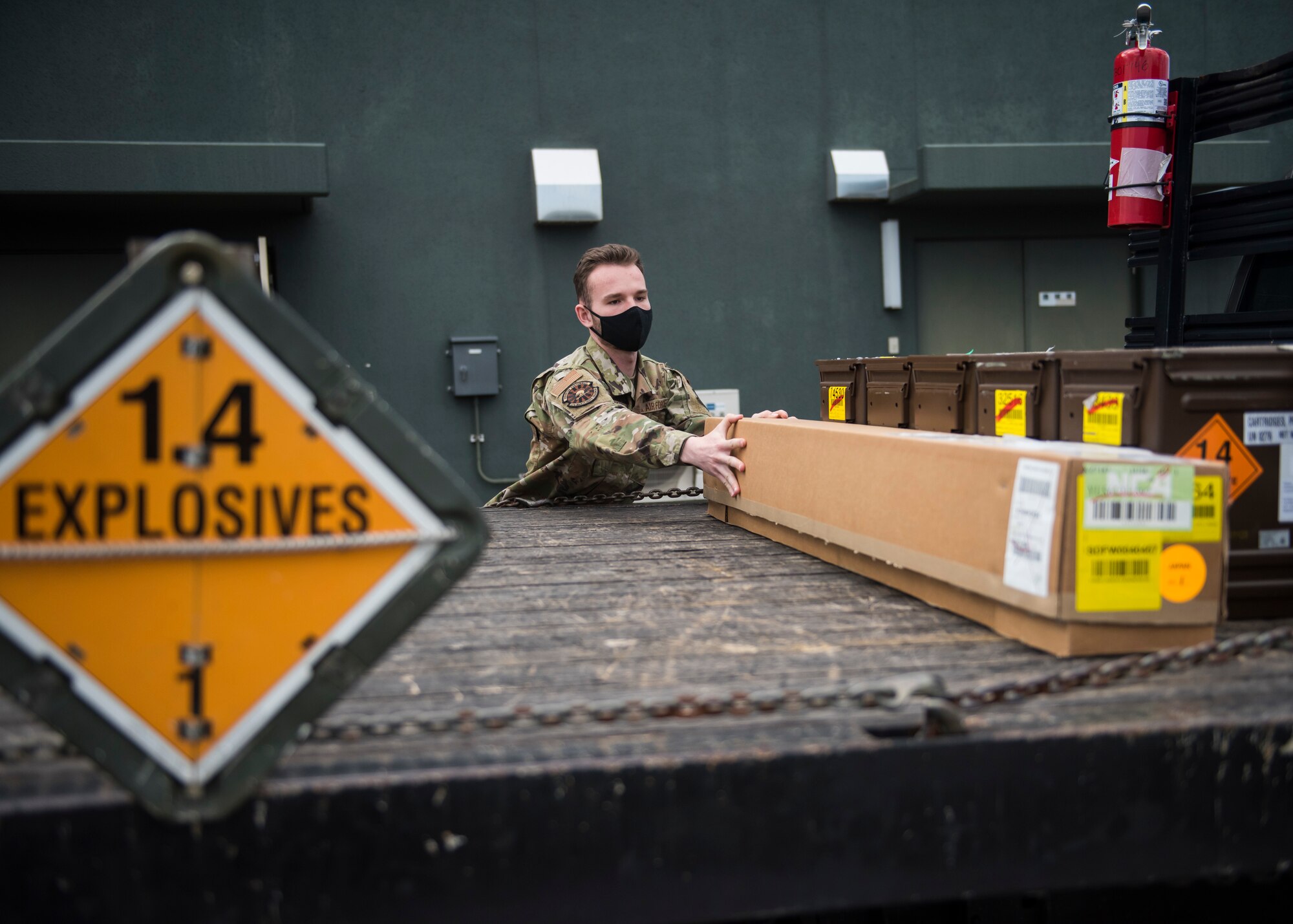 Man in uniform moves boxes of f-35 egress parts onto a truck bed for transportation.