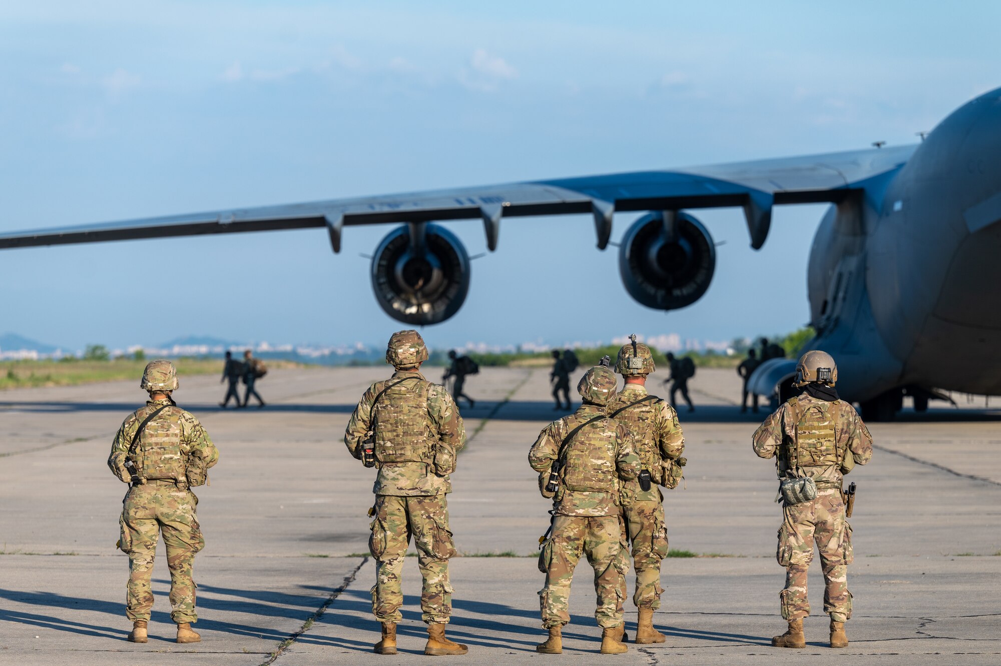 Airmen and Soldiers stand next to an aircraft on an airfield.