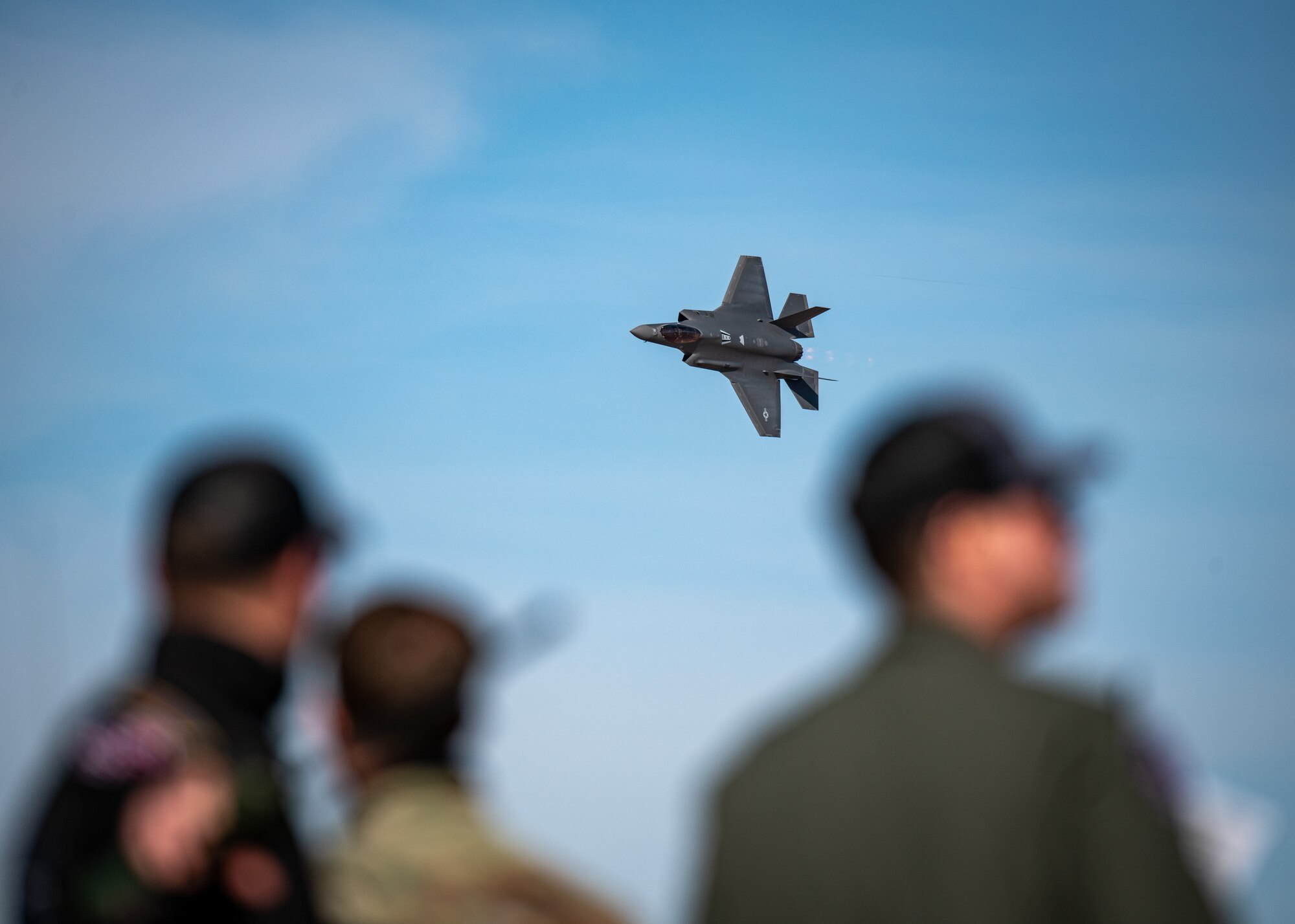 People look at an F-35A Lightning II in the air