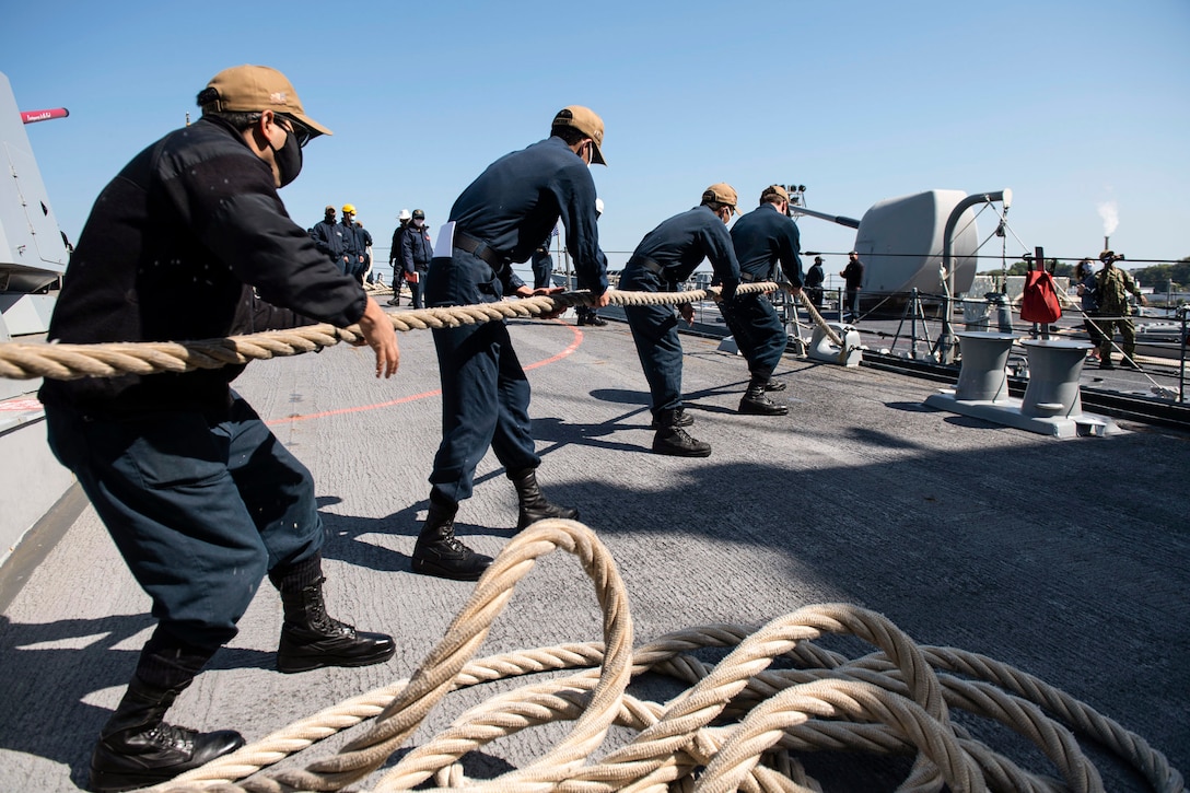 A group of sailors pull a rope.