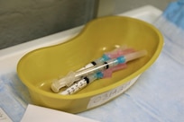 syringes loaded with COVID vaccines sit in a yellow pan ready to be administered
