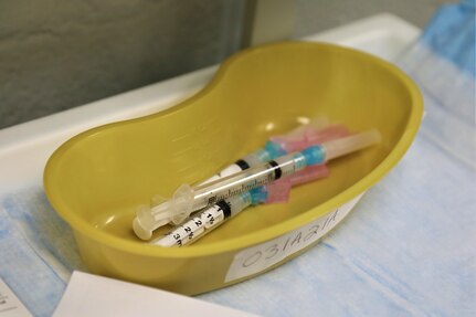 syringes loaded with COVID vaccines sit in a yellow pan ready to be administered