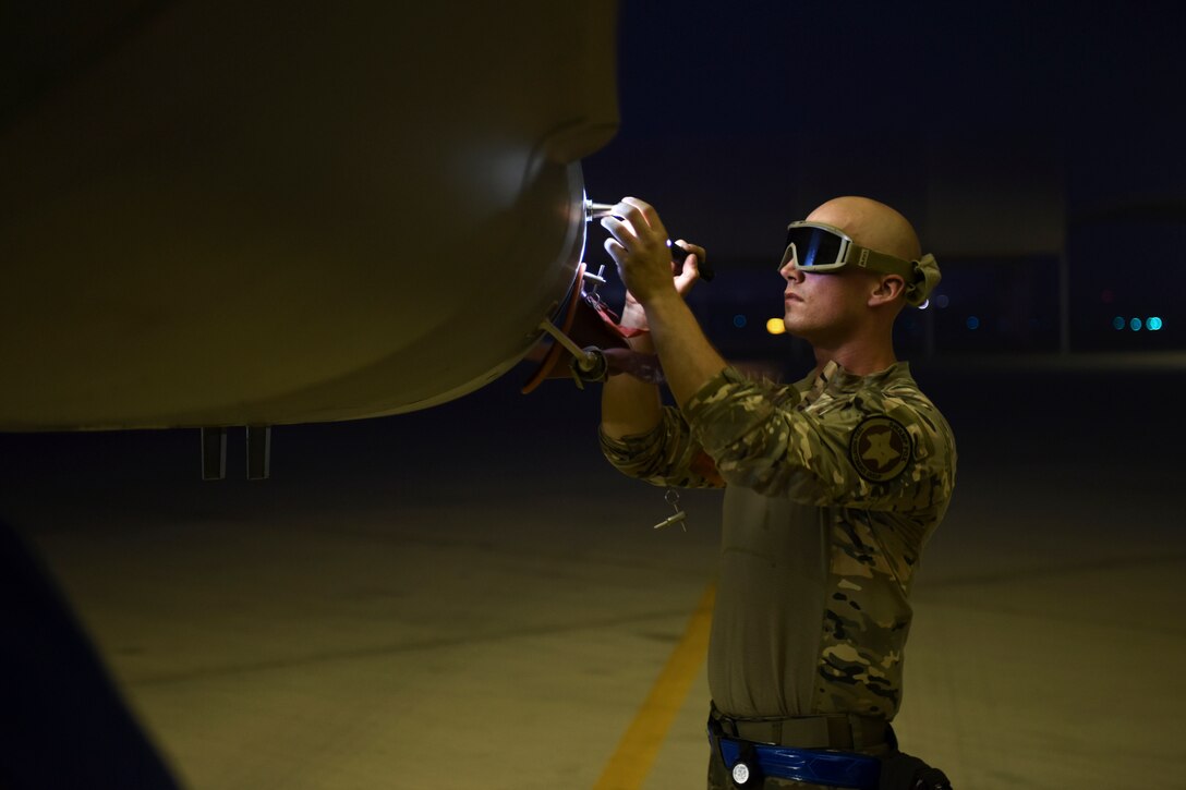 An airmen inspects an aircraft in the dark.