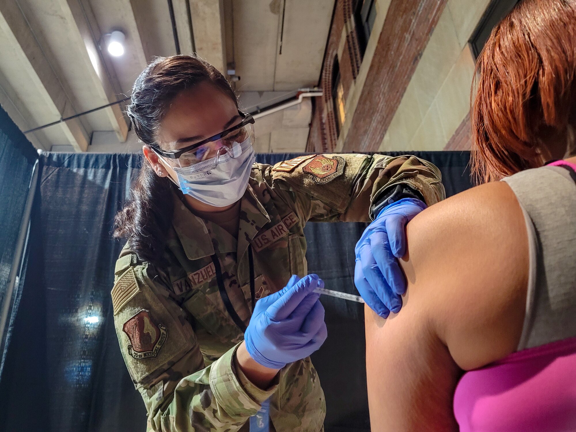 U.S. Airman 1st Class Pollyann Valenzuela, a Los Angeles native and medic with the 75th Medical Group stationed at Hill Air Force Base, Utah, assigned to 1st Detachment, 64th Air Expeditionary Group, administers a COVID-19 vaccination to a local community member at the state-run, federally-supported Ford Field COVID-19 Community Vaccination Center in Detroit, March 26, 2021. The Ford Field CVC is being supported by members of the Federal Emergency Management Agency, Henry Ford Health Systems, Michigan Department of Health, Meijer and the U.S. Air Force. U.S. Northern Command, through U.S. Army North, remains committed to providing continued, flexible Department of Defense support to FEMA as part of the whole-of-government response to COVID-19. (U.S. Army photo by Spc Andrew Wash, 5th Mobile Public Affairs Detachment)