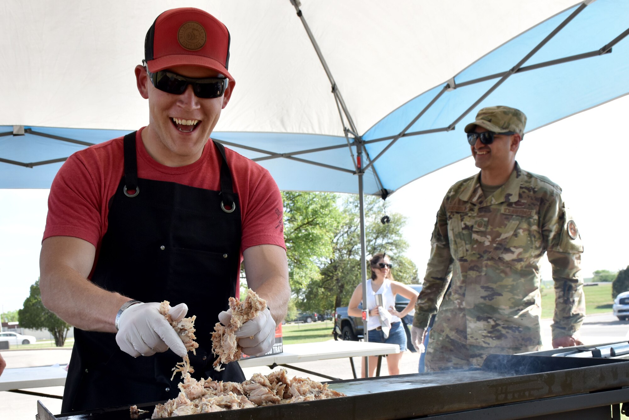 Individual placing chicken on a grill outdoors.