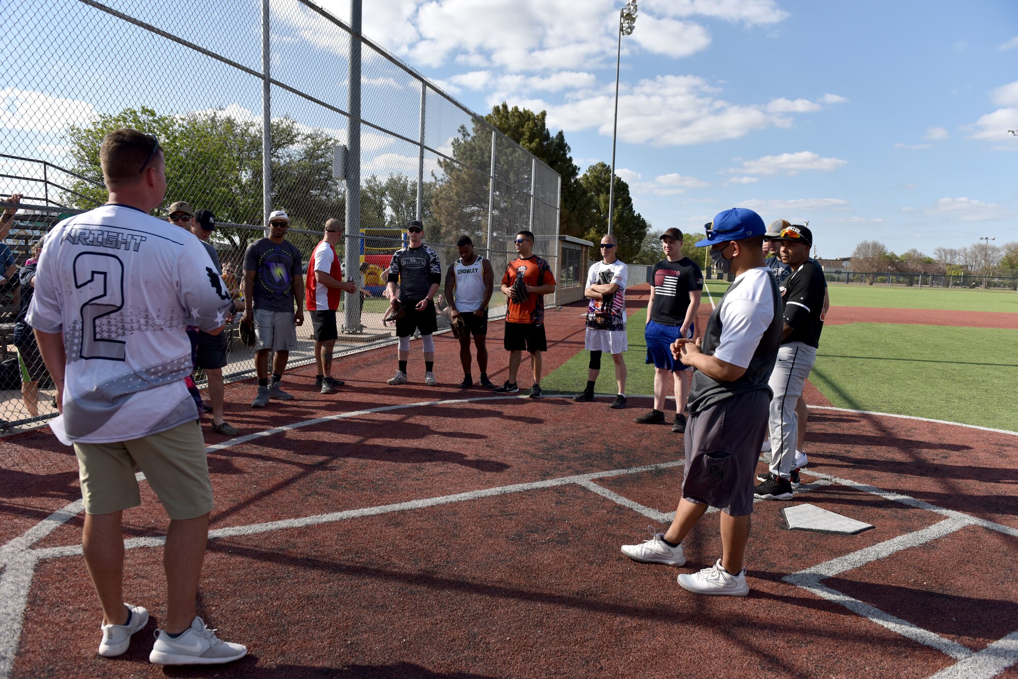 Group of individuals listening to rules before beginning a game of softball.