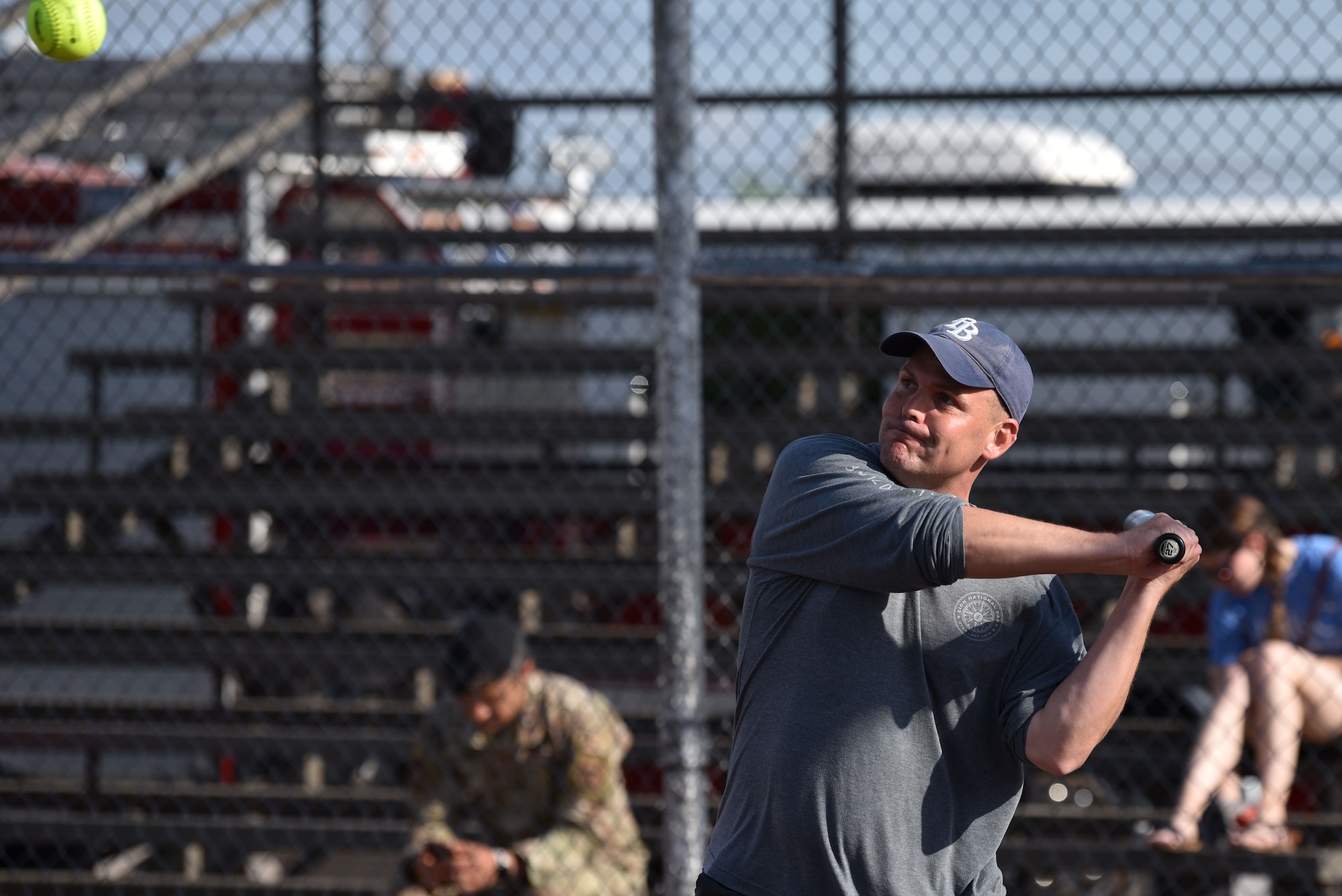 Individual swinging bat towards a softball.