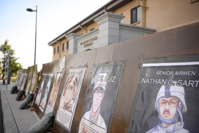 Posters of the 16 Security Forces Airmen who lost their lives on duty are displayed during a Police Week ceremony.