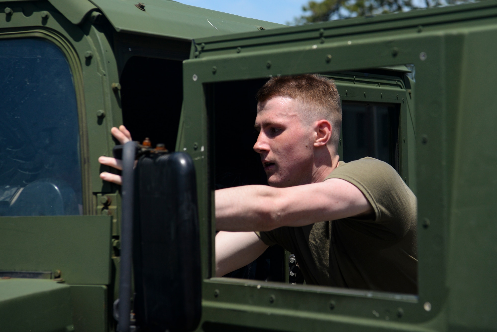 An Airman pushes a Humvee.