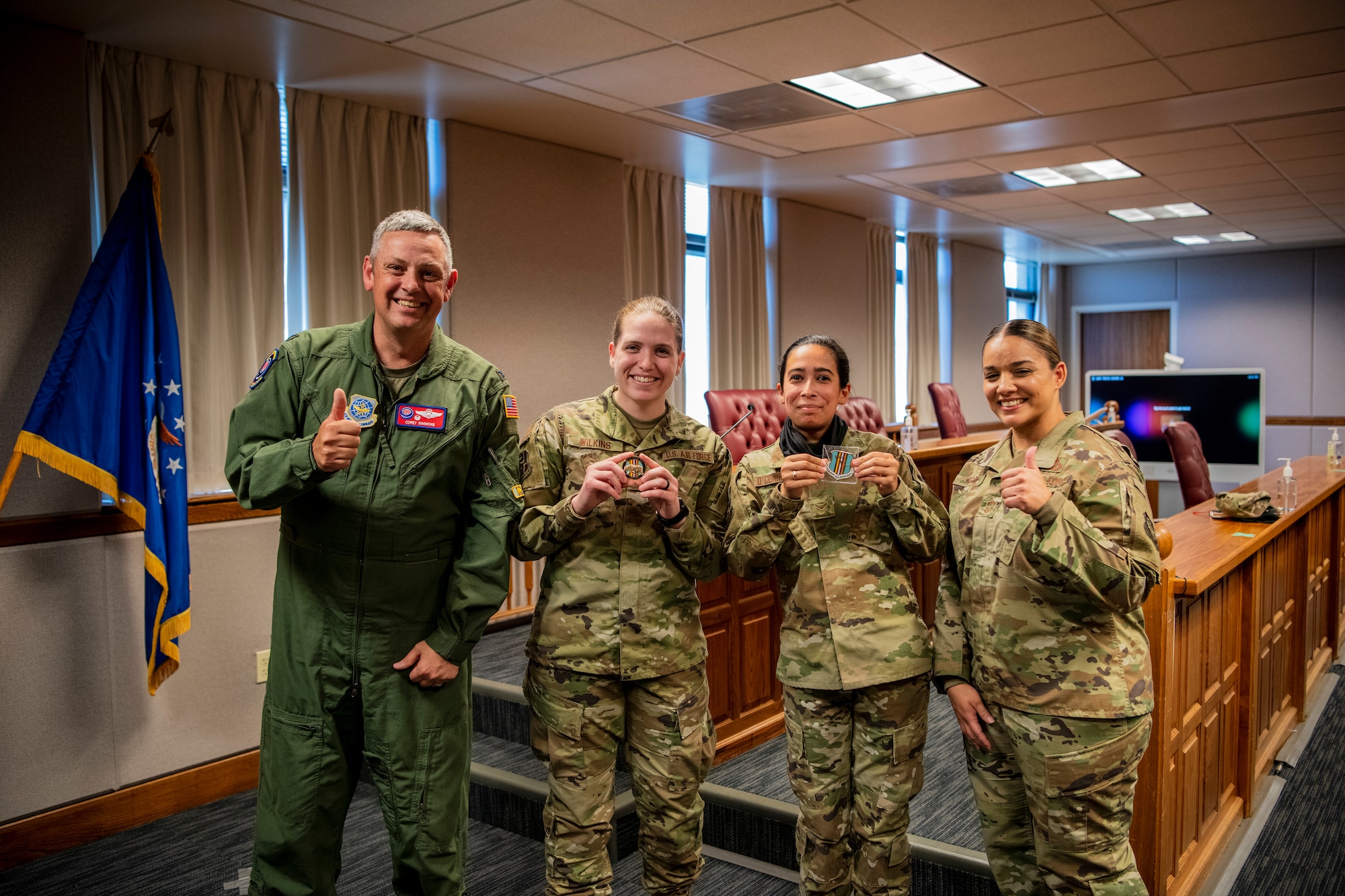 Four Airmen are standing next to each other, the two Airmen in the center are holding coins they just received from base leadership.